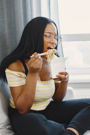 Beautiful young african american woman eating noodlesの写真素材
