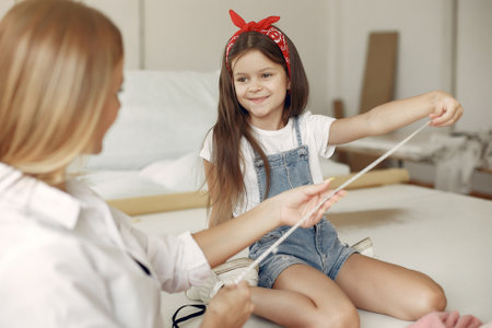 Mother with little daughter measure the fabric for sewingの写真素材