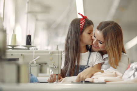 Mother with little daughter sew clothes in the factoryの写真素材