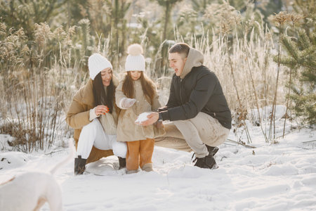 Family in winter clothes play in winter forest