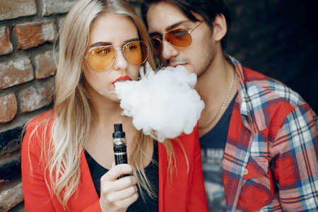 Stylish young couple with vape in a cityの写真素材