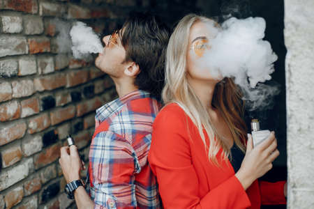 Stylish young couple with vape in a cityの写真素材