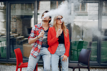 Stylish young couple with vape in a city