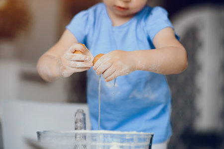 Child in a kitchen. Little girl with a dough. Kid in a blue t-shirtの写真素材