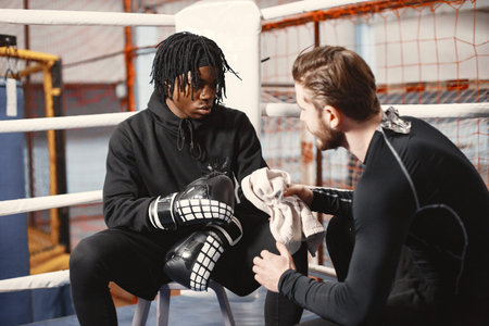 Male boxer in black gloves with caucasian coach