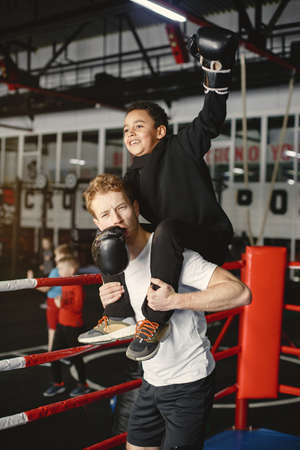 Little boy in boxing gloves on ring with trainerの写真素材