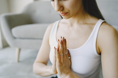 Girl doing yoga exercises at home near sofa and window in sportswear