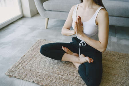 Girl doing yoga exercises at home near sofa and window in sportswearの写真素材