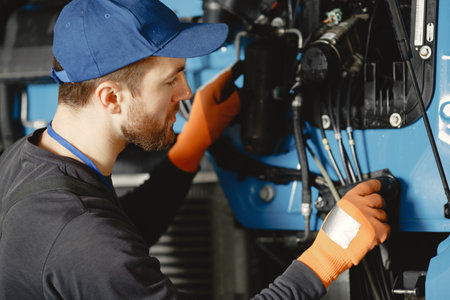 Worker checks quality of truck in garage in uniformの写真素材
