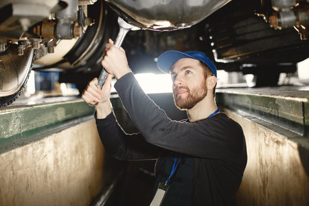 ar mechanic repairs blue car on rise in garage