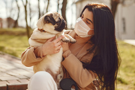 Brunette in a mask walks with pugの写真素材