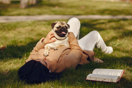 Brunette in a brown coat walks with pugの写真素材