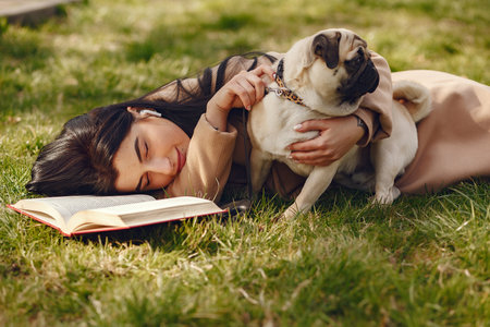 Brunette in a brown coat walks with pugの写真素材