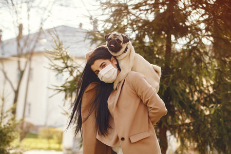 Brunette in a mask walks with pugの写真素材