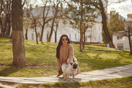 Brunette in a brown coat walks with pugの写真素材