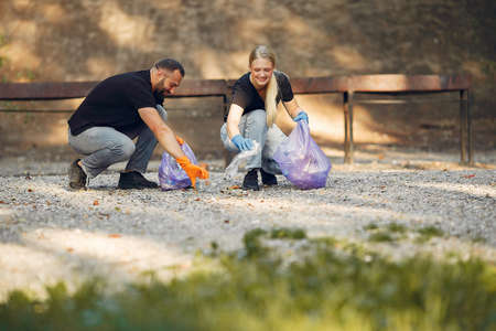 Couple collects garbage in garbage bags in parkの写真素材
