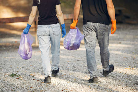 Couple collects garbage in garbage bags in parkの写真素材
