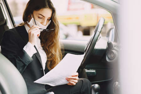 Businesswoman in a black mask sitting inside a carの写真素材