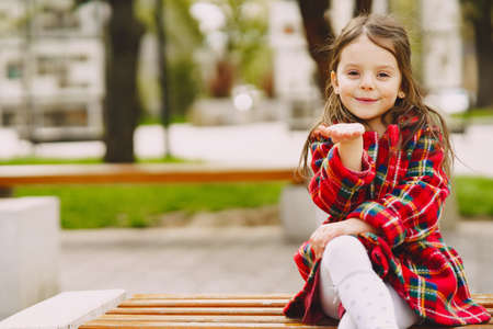 Little girl in a park sitting on a benchの写真素材
