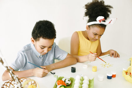 Children in yellow clothes paint Easter eggs