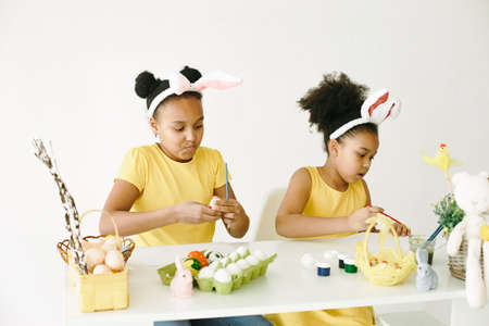 Children in yellow clothes paint Easter eggsの写真素材