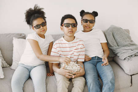Boy watching a movie on couch in 3d glasses with popcornの写真素材