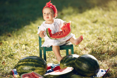 Cute little girl with watermelons in a parkの写真素材