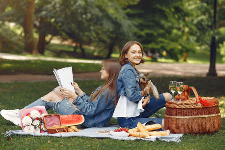 Two cute girls in a park playing with little dogの写真素材