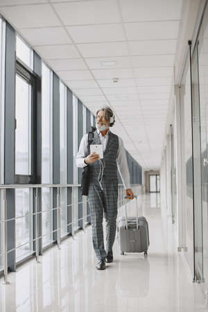 Senior businessman with travel suitcase in airportの写真素材