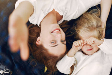 Mother with little daughter lying on a plaid in a summer parkの写真素材