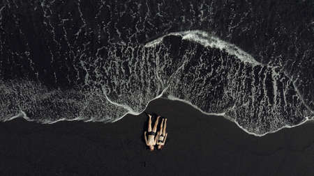 Couple lie on a black sand near oceanの写真素材