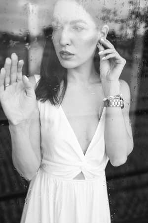 Girl stands by the glass by the windowの写真素材