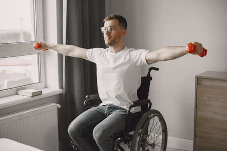 Young man in wheel-chair doing exercises indoorsの写真素材