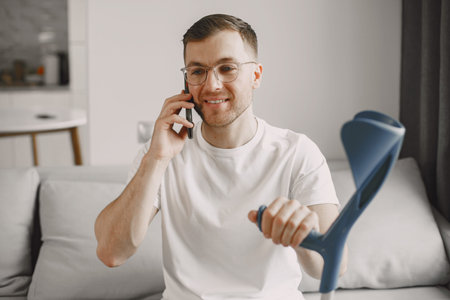 Young man with walking stick talk by phone indoors