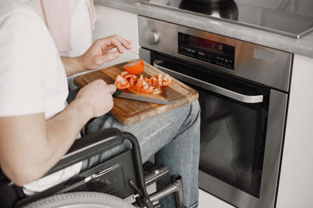 Disabled Young Man in Wheelchair Preparing Food In Kitchen