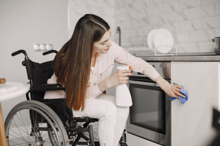 Young Handicapped Woman On Wheelchair Cleaning Stoveの写真素材