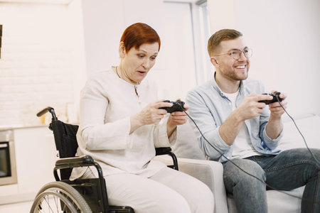 Senior handicapped woman play videogames with son