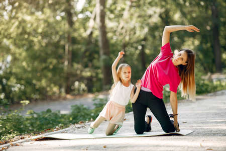 Mother with daughter doing yoga in a summer parkの写真素材