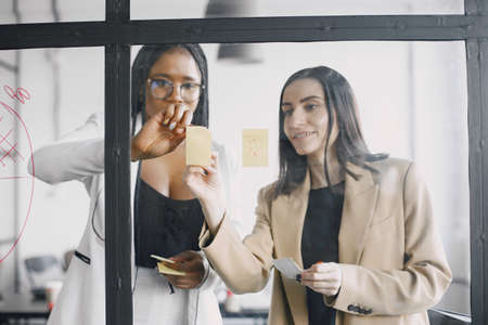 Businesswoman talking and writing on transparent board at modern officeの写真素材