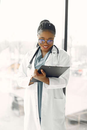 African doctor standing by window with a folderの写真素材