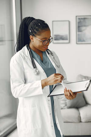 African doctor standing by window with a folderの写真素材