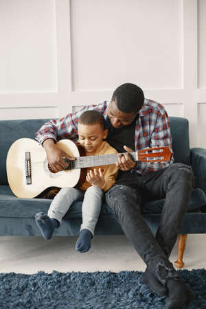 Father teaches his son to play guitarの写真素材