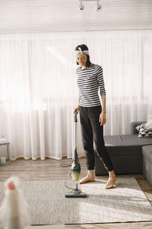 Woman vacuuming mat at home in a good moodの写真素材