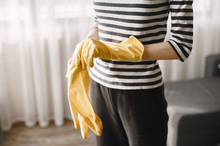 Woman in yellow gloves cleans her home