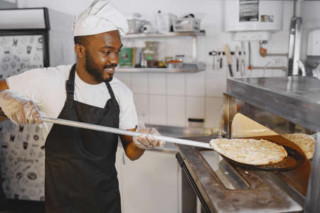 African merican man baking pizza at commercial kitchenの写真素材