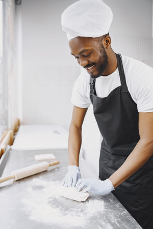 Cheerful chef preparing dough for pizza at bakery