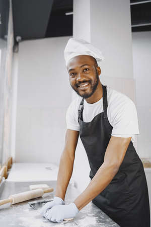 Cheerful chef preparing dough for pizza at bakeryの写真素材