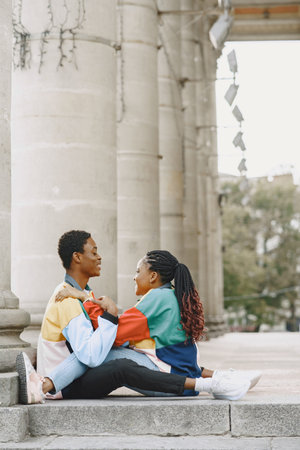 Ethnic couple sitting in city street