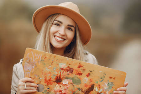 Woman in a brown coat painting in a fieldの写真素材