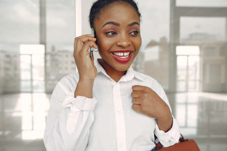 Black woman standing in the office with a laptopの写真素材
